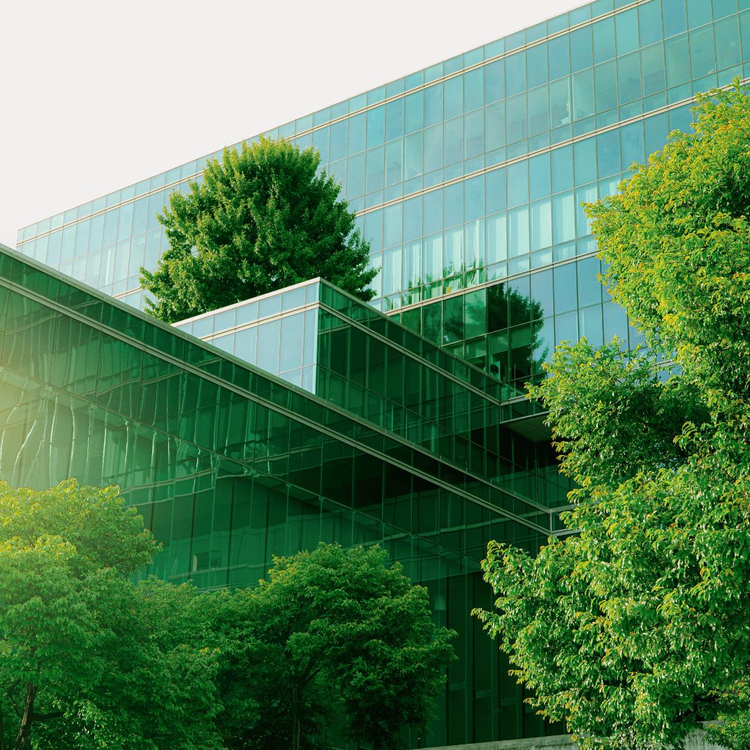 Een glazen gebouw omringd met groene bomen.